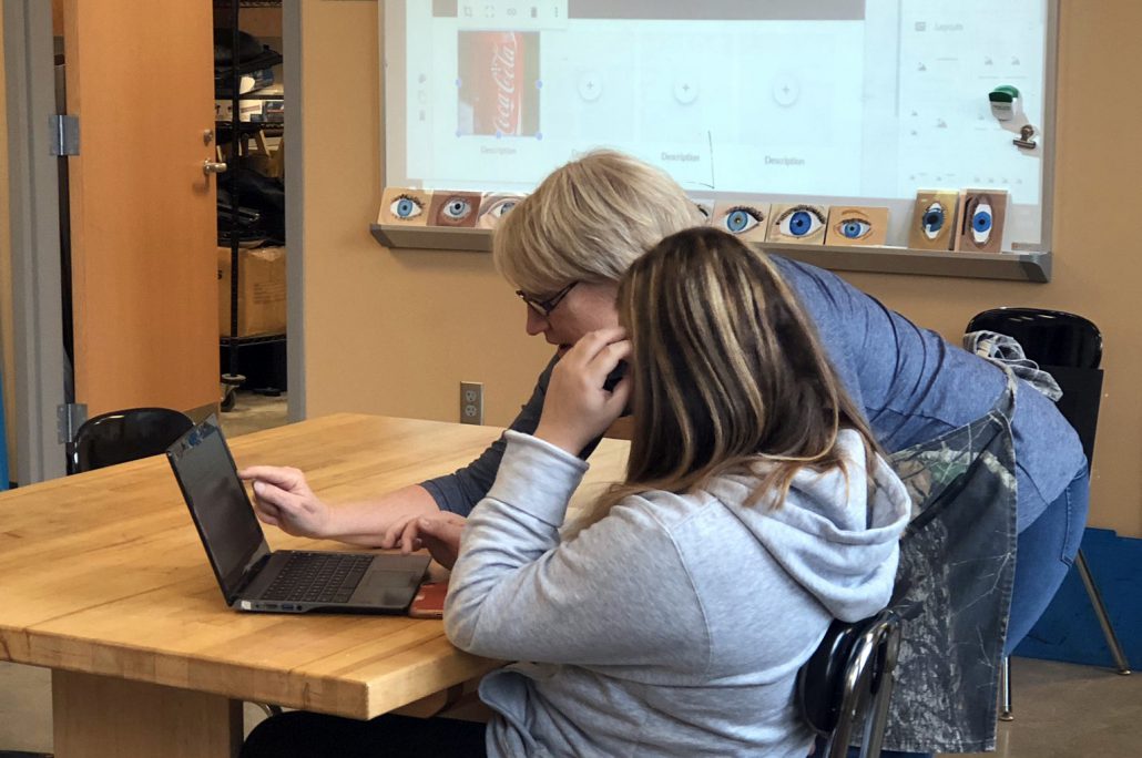 Image of Teacher Working with Student on Laptop in Class