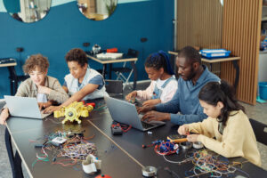 High angle view at diverse group of children with male teacher building robots during engineering class in school
